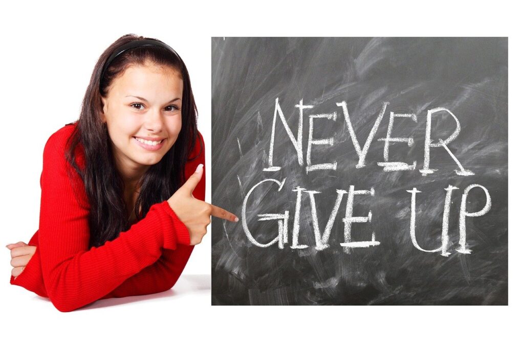 Une fille montre un tableau sur lequel est écrit "Never Give Up"