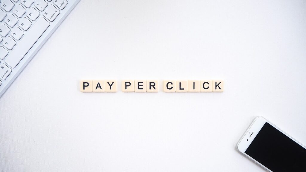 Un clavier, un smartphone et les mots "PAY PER CLICK" posés sur une table