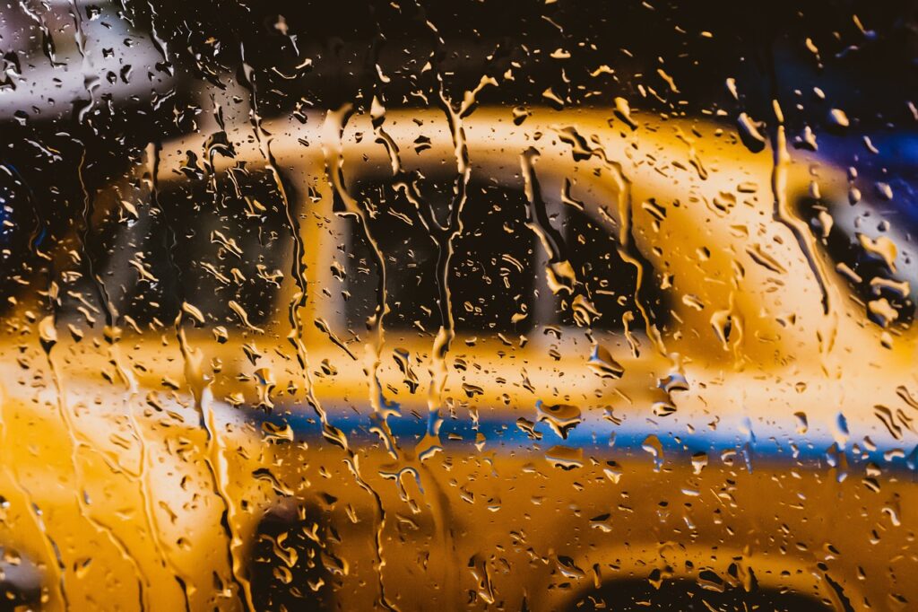 Un taxi jeune vu à travers une vitre sous la pluie